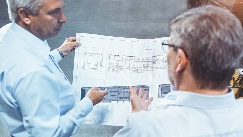 Projektleiter und Ingenier blicken auf Konstruktionsplan für industrieofenanlage